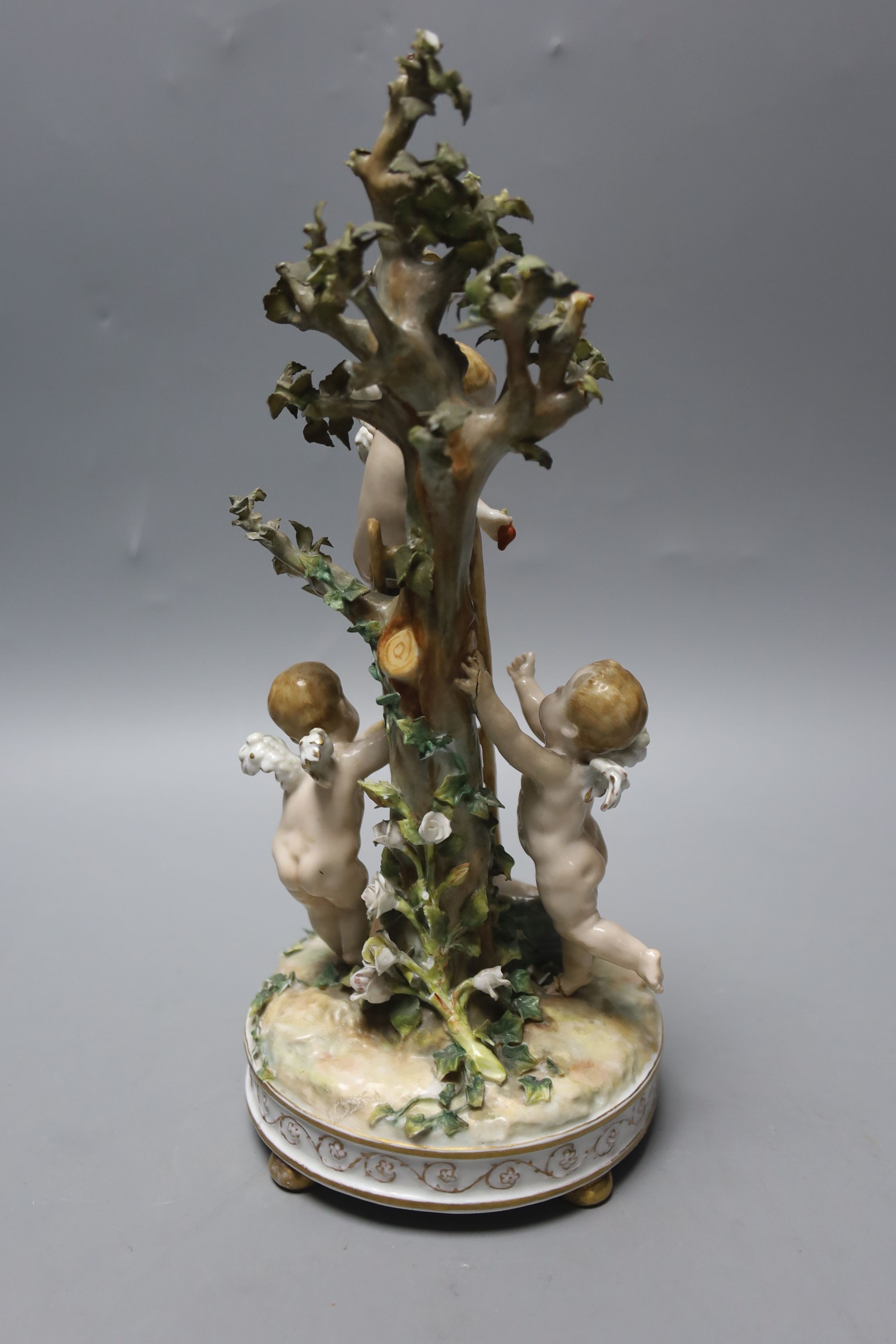 A German porcelain Meissen style group of amorini, climbing a ladder to pick fruit from a tree, small losses, 27cm